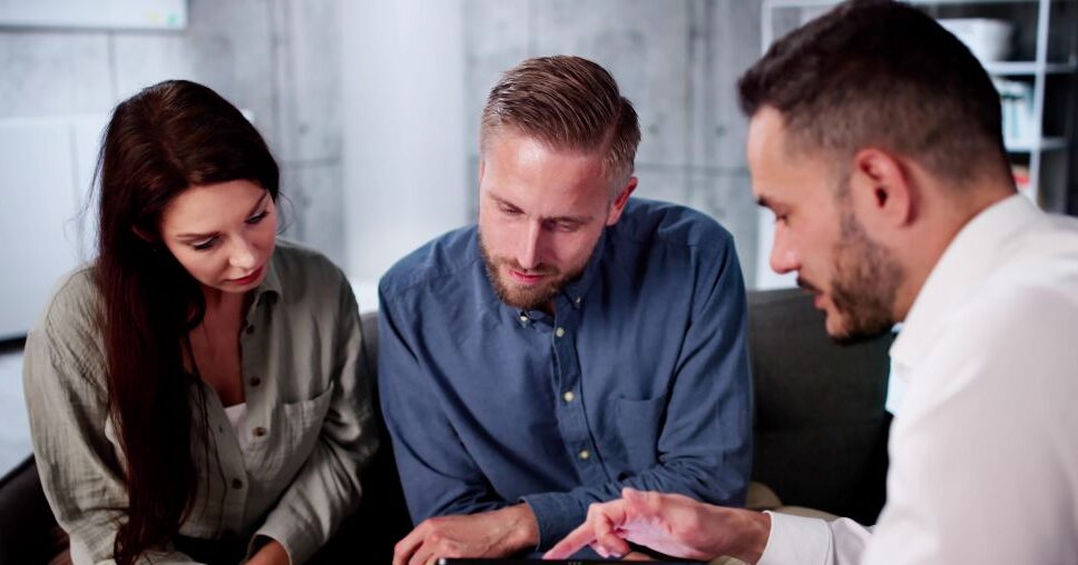 couple talking with salesman showing tablet