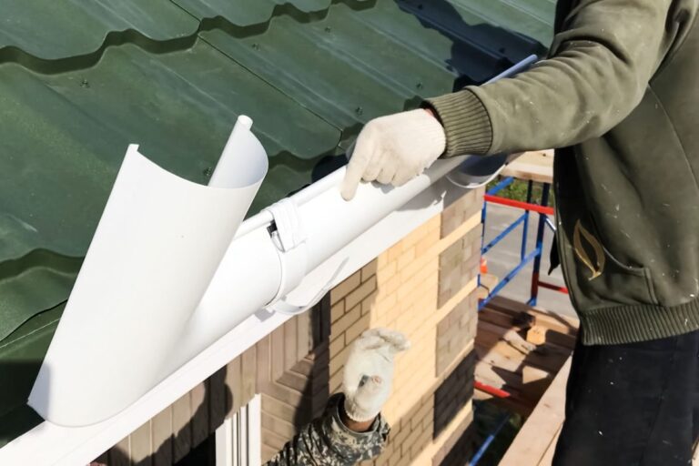 green metallic tiles worker installing gutter system