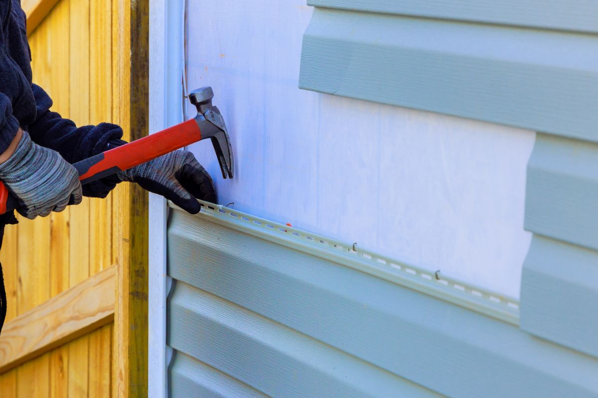 worker gloves siding repair using hammer