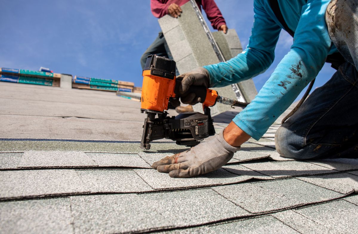 worker installing asphalt shingles roof