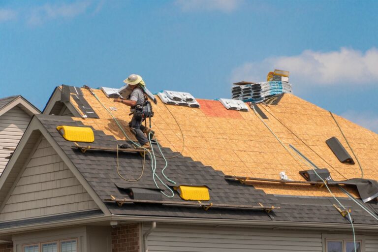 worker installing shingles roof