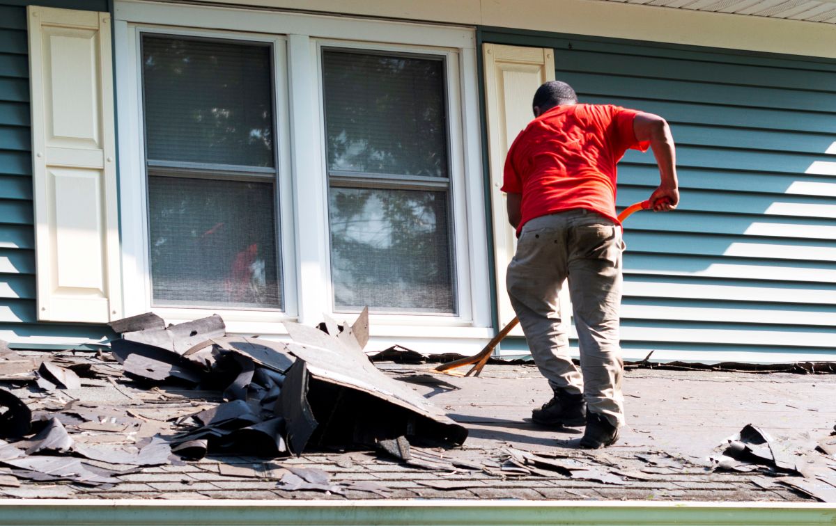 worker replacing shingles using shovel