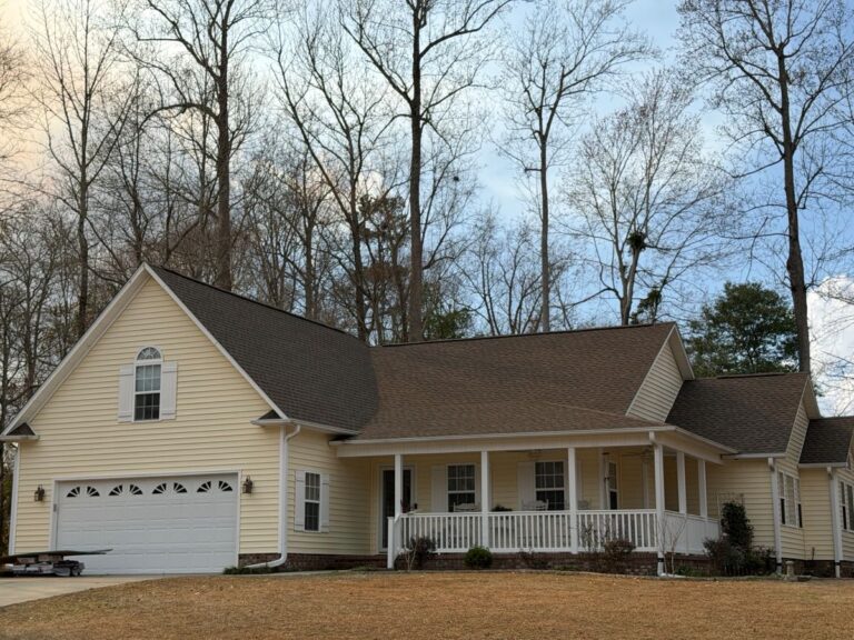 A pale yellow house with a shingle roof