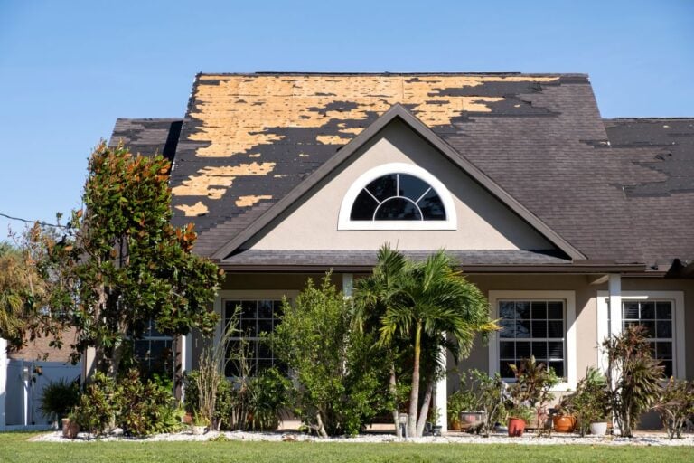 Wind damaged house roof with missing asphalt shingles