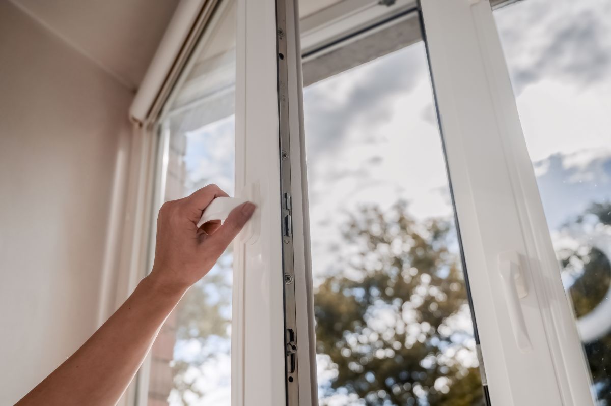 a hand opening a white window