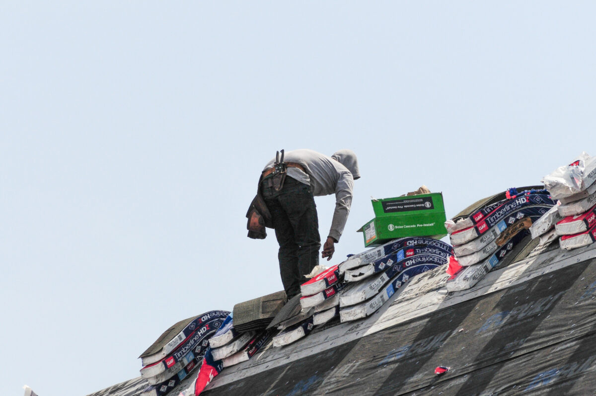 synthetic roofing underlayment worker installing shingles on residential roof